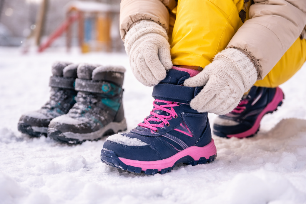zimowe buty dziecięce zakładane przez dziecko na śniegu podczas zabawy na zewnątrz